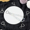 A set of heart-shaped spring hook keychains displayed on a white plate against a dark fabric background.