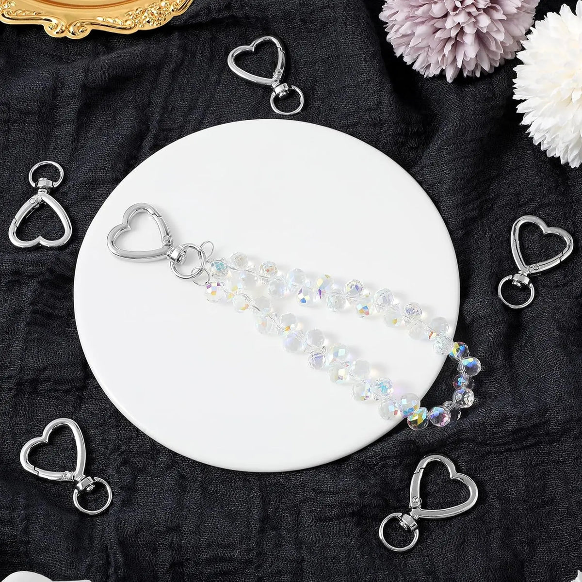 A set of heart-shaped spring hook keychains displayed on a white plate against a dark fabric background.