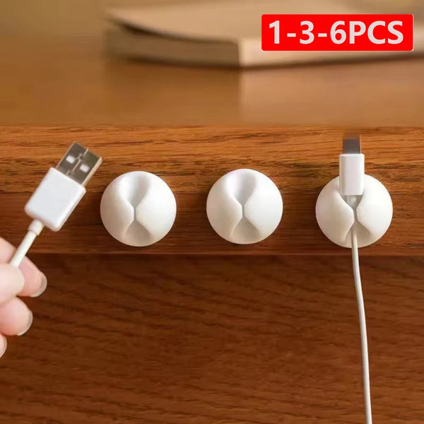 A set of silicone cable clips and organizers for managing wires on a wooden surface.