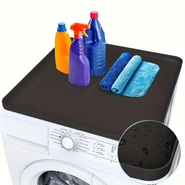 A silicone protector mat is shown on a washing machine top with various cleaning bottles and blue towels.