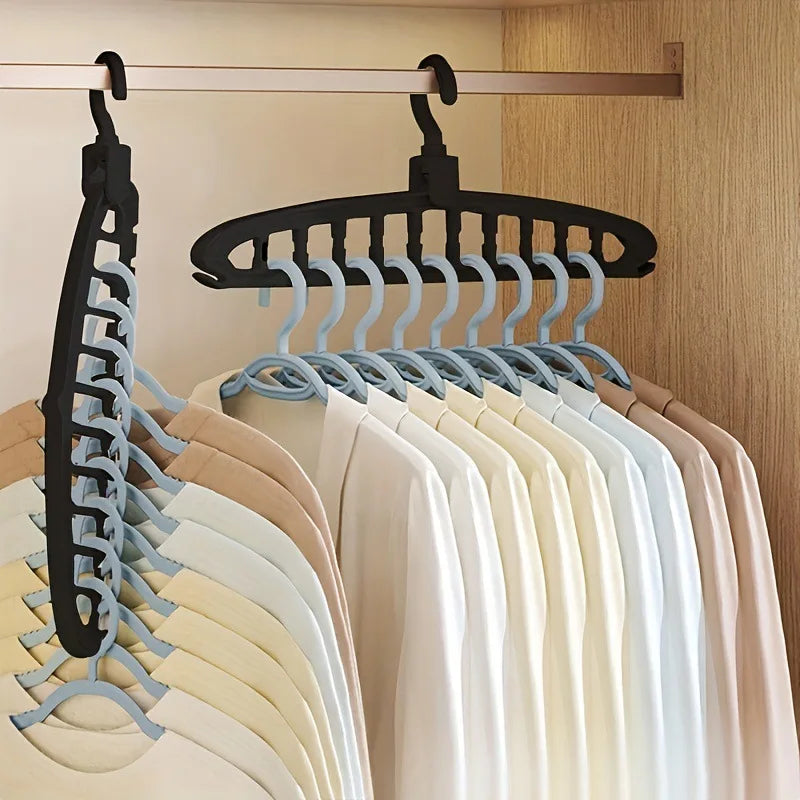 A wooden clothes rack with black hangers displaying various light-colored shirts and blouses.