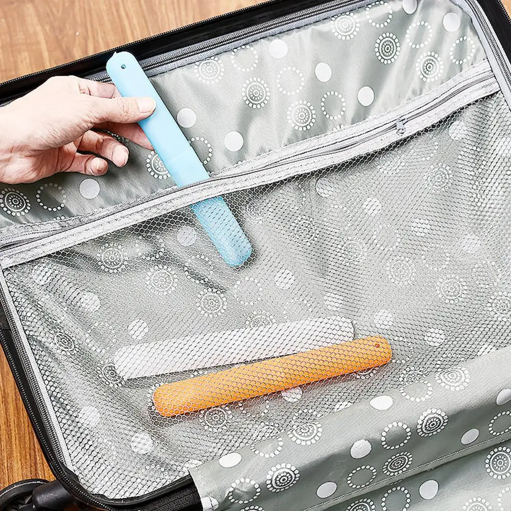 A hand is placing a light blue portable toothbrush into a silver mesh storage case.
