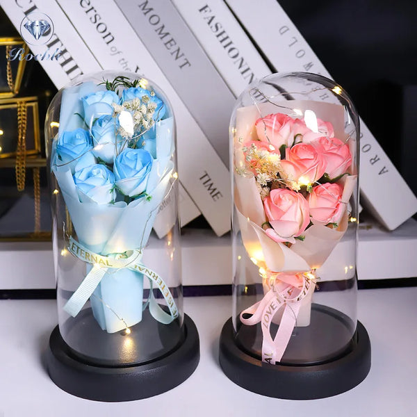 A glass display featuring a bouquet of blue roses and pink roses illuminated by LED lights.