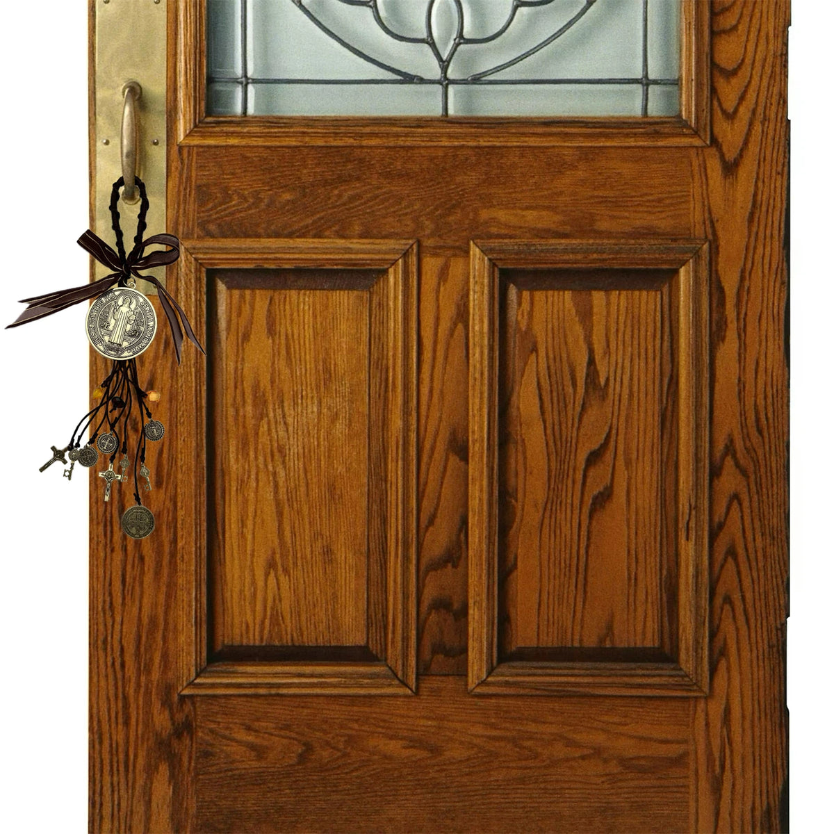 Nahaufnahme einer Holz-Tür mit Glaspaneel und einem antiken Silber-St. Benedikt-Medalons als Anhänger.