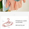 A set of portable plastic clothes hangers in various colors including beige, orange, pink, and blue hanging on a wooden rod.