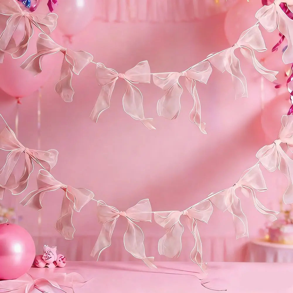 Pink decorative bowknot banner garland set strung across a pink background with balloons