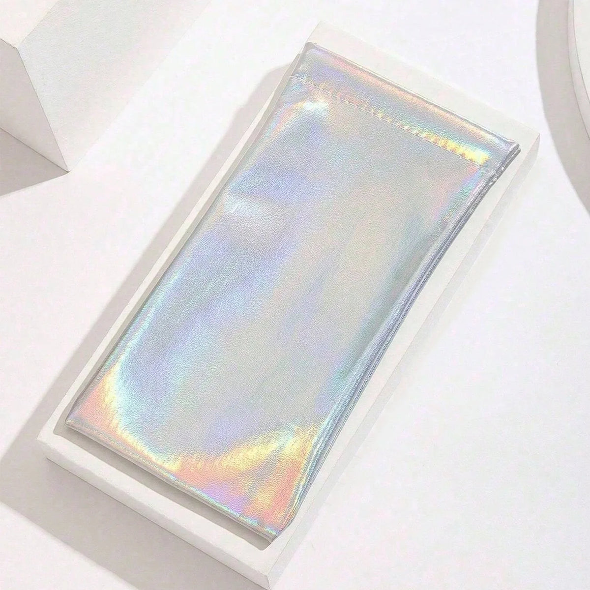 A rectangular PU leather squeeze eyeglasses case with a iridescent, holographic finish is displayed on a white surface.