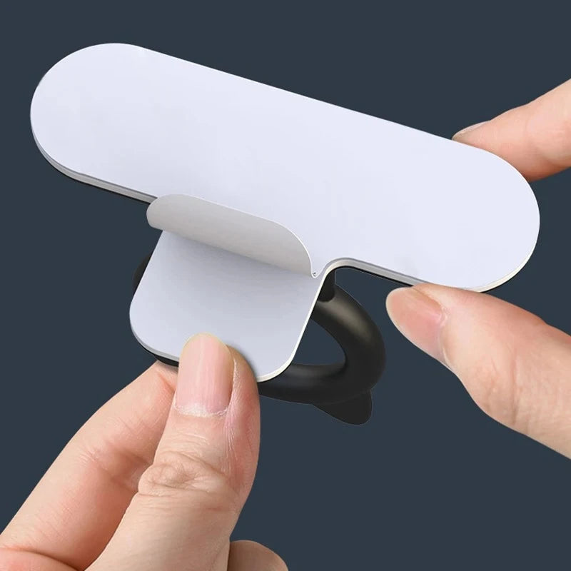A hand is lifting a white silicone self-adhesive cabinet door handle lifter.