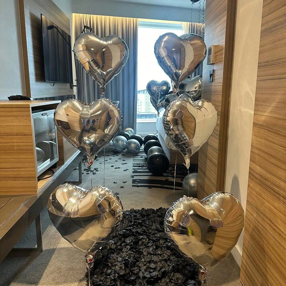 A collection of silver and gold heart-shaped balloons displayed in a room setting.