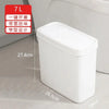A white slim bathroom trash can with a press lid shown next to a toilet.