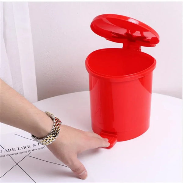 A hand is holding a bright red reusable decorative strawberry pop-up trash can with its lid open.