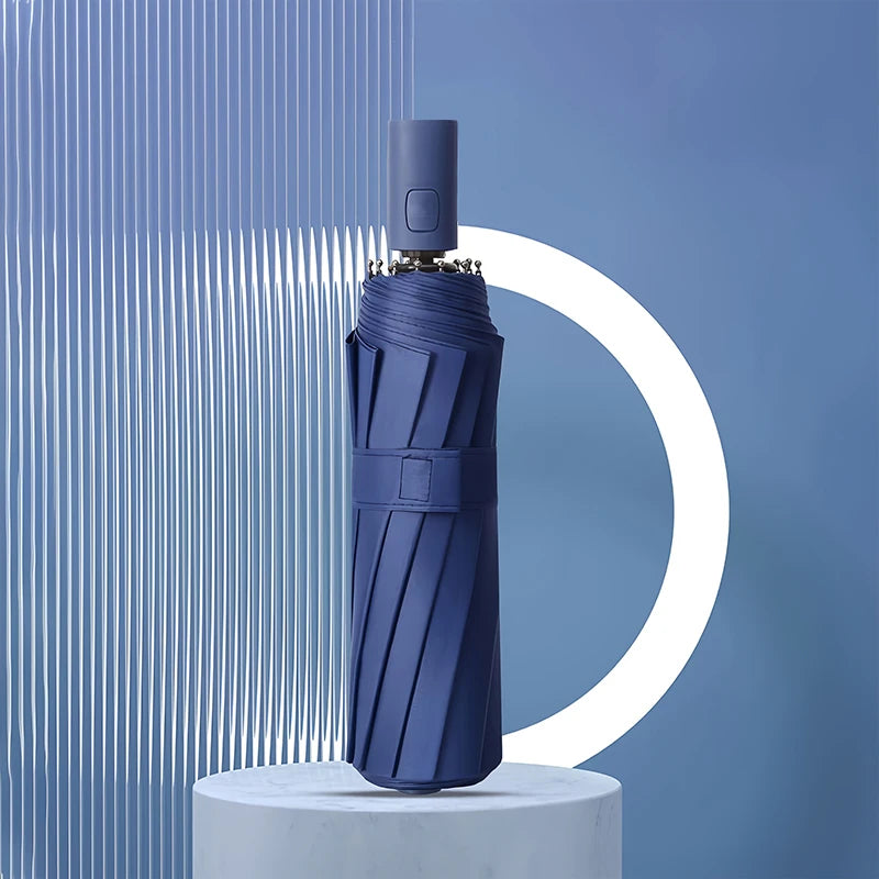 A dark blue heavy duty automatic windproof umbrella standing on a white pedestal against a blue background.