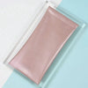A pink PU leather squeeze eyeglasses case with a soft lining resting on a light blue surface.