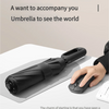 A black windproof automatic folding umbrella resting on a table next to a hand.