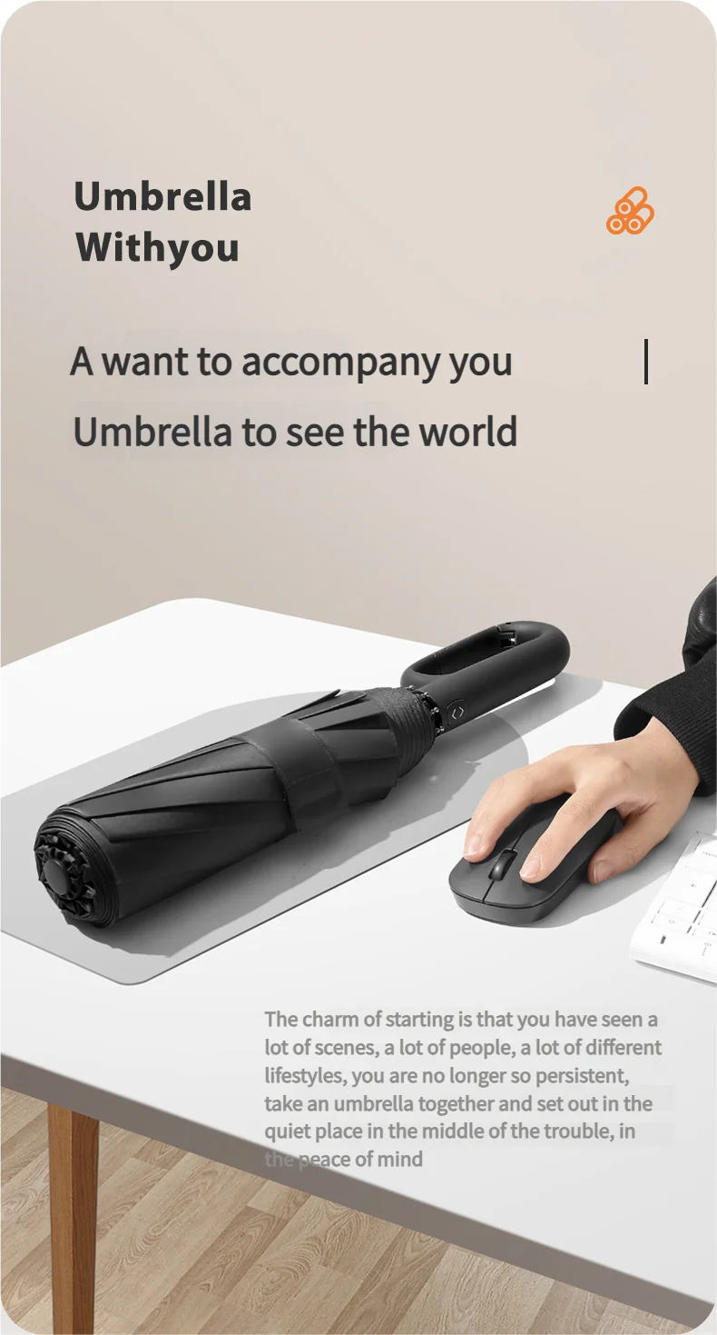 A black windproof automatic folding umbrella resting on a table next to a hand.
