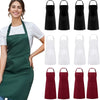 A woman models a dark green chef apron and several black and white aprons.