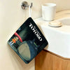 A dark green cartoon print of Totoro hanging on a wall, next to a white cup and sink.