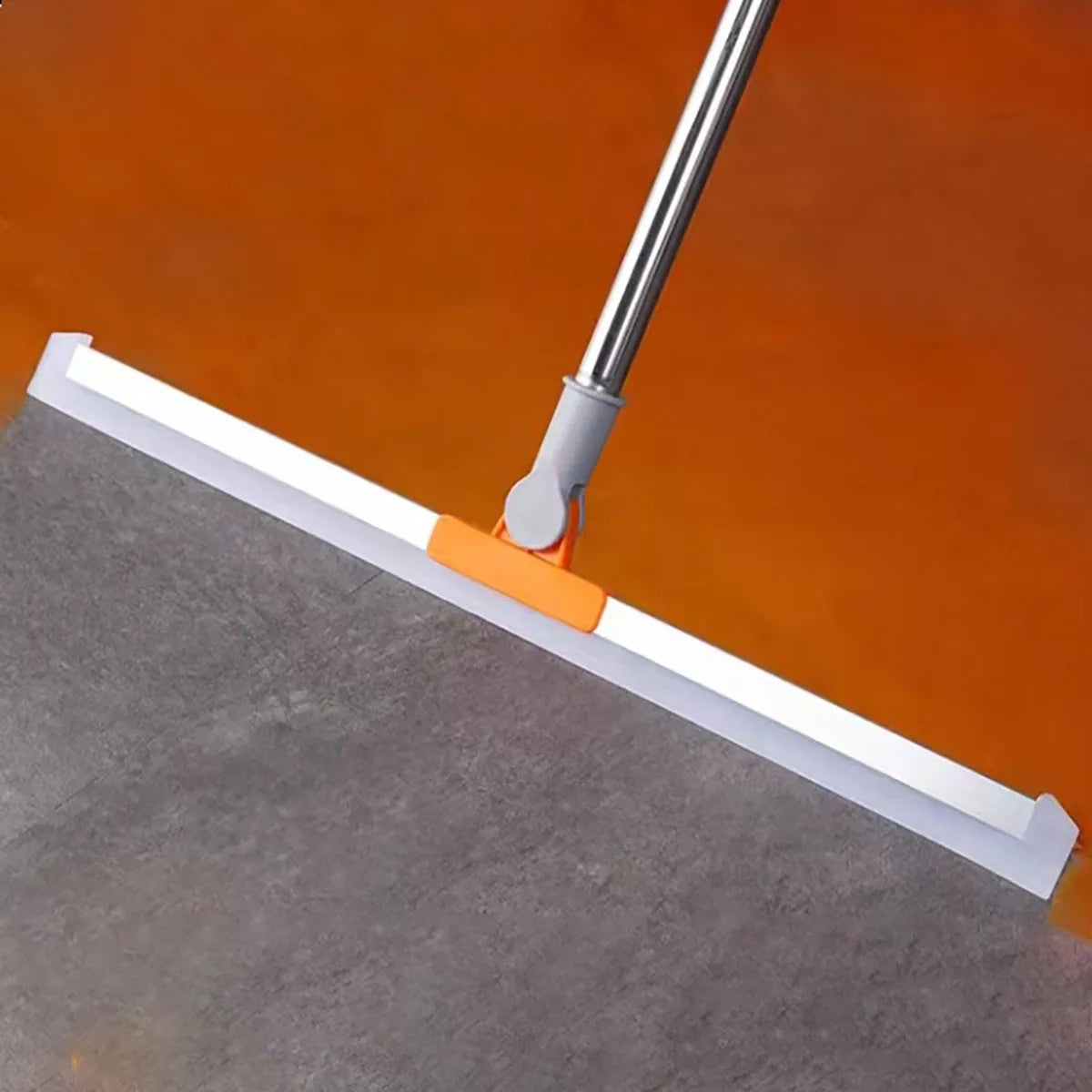 A silicone squeegee broom with an aluminum handle is shown cleaning a dark surface against an orange background.