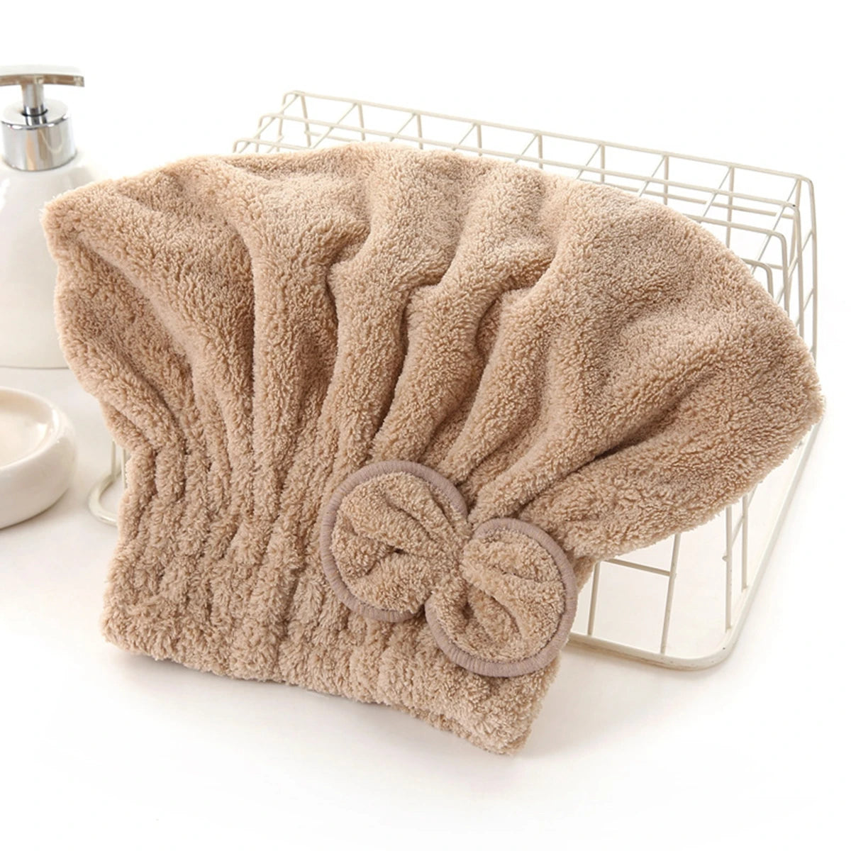A beige microfiber hair drying cap and towel is displayed on a wire rack.