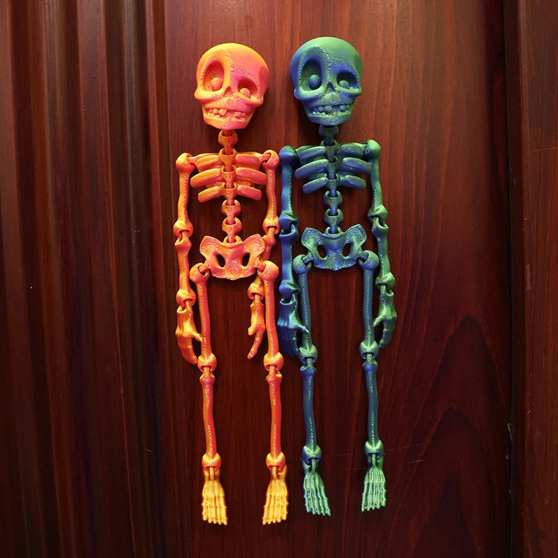 Two poseable skull fridge magnets, one orange and one blue, displayed against a dark wooden background.