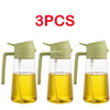 Three glass oil spray bottles with green caps and yellow cooking oil inside