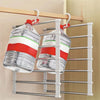 A silver multi-layer pants hanger with red and white clips is displayed on a wooden rack.