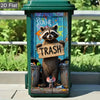 Un cubo de plástico verde decorado con una figura de mapache y un cartel de basura, instalado al aire libre.