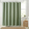 A light sage green waffle weave shower curtain hanging on a metal rod in a bathroom setting.