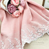 Rosa Leinen-Baumwoll-Apronkleid mit weißer Spitze und Blumenstickerei auf hellem Hintergrund