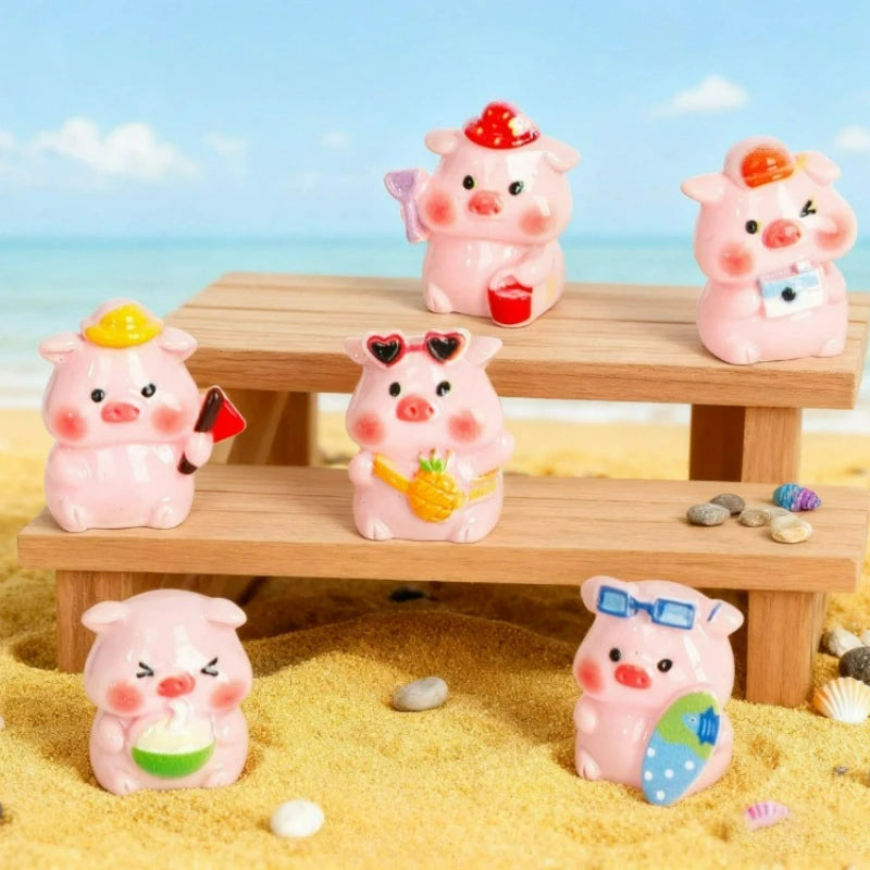Una colección de miniaturas de cerdos de resina rosa sobre una tabla de madera en una playa arenosa.