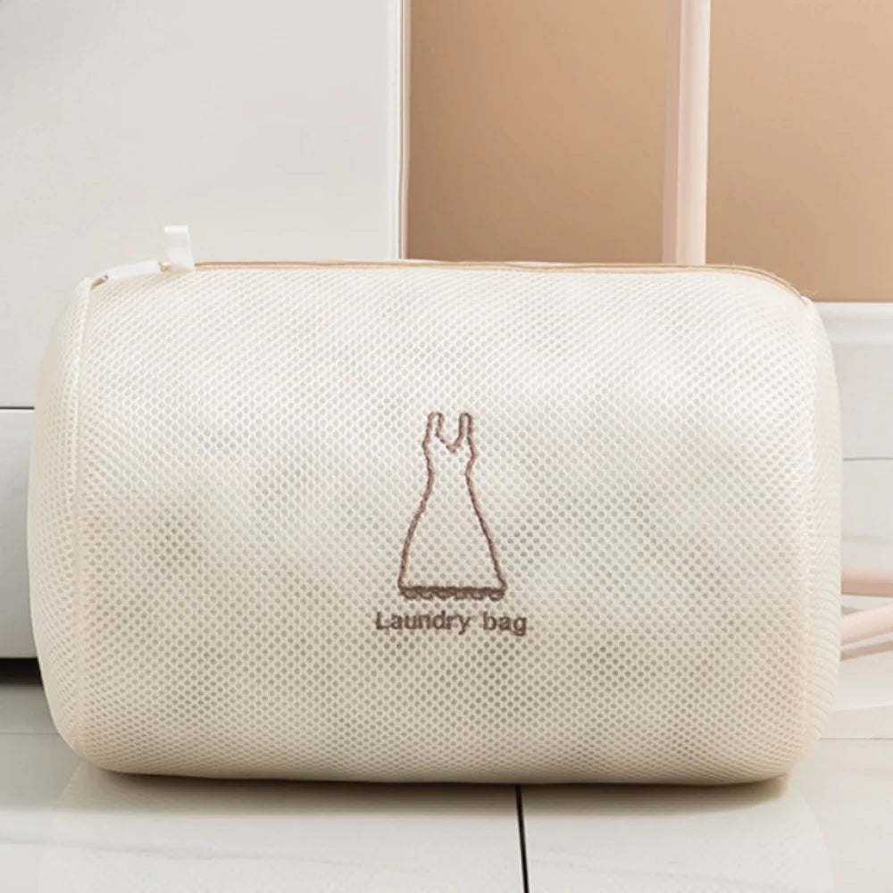 A cream-colored reusable zippered laundry bag lying on a white surface.