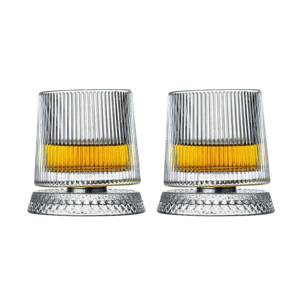 Un par de vasos de whisky texturizados y acanalados con líquido ámbar y bases de plata.