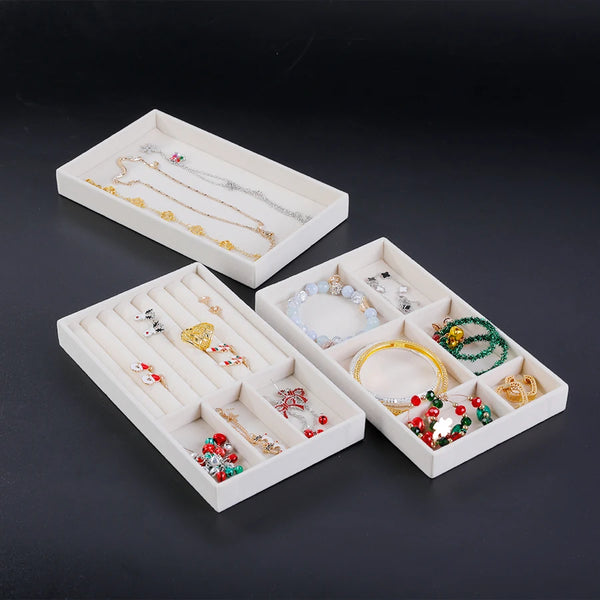 A white velvet jewelry organizer tray with drawers displaying various gold and silver necklaces and rings.