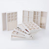 A set of white velvet jewelry organizer trays and drawers displayed on a white background.