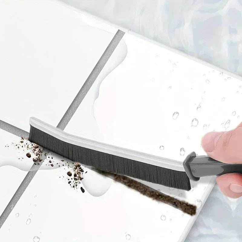 A close-up of a black hard-bristle crevice cleaning brush being used to clean a white surface.