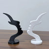 A pair of minimalist 3D printed profile eyeglass stands in black and white on a wooden surface.