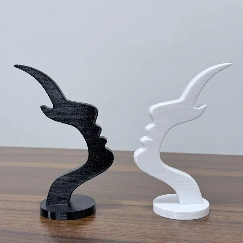 A pair of minimalist 3D printed profile eyeglass stands in black and white on a wooden surface.