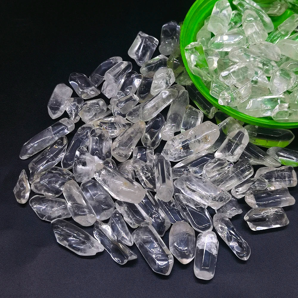 Una colección de cristales de cuarzo claros y piedras translúcidas se exhiben junto a un tazón verde.