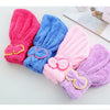 Three fuzzy microfiber hair drying towel caps in pink, blue, and purple are displayed on a white surface.