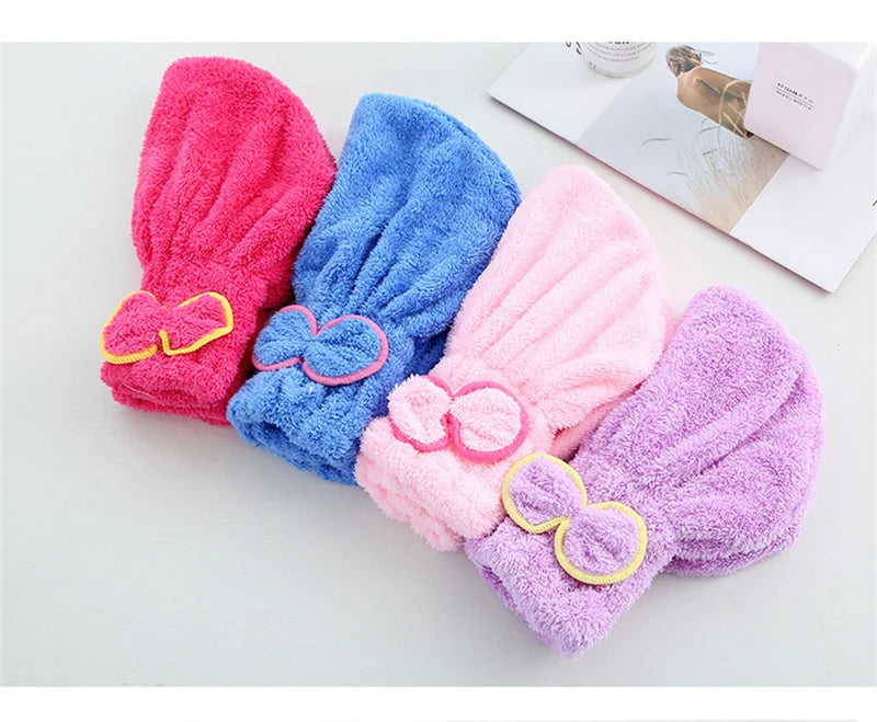 Three fuzzy microfiber hair drying towel caps in pink, blue, and purple are displayed on a white surface.