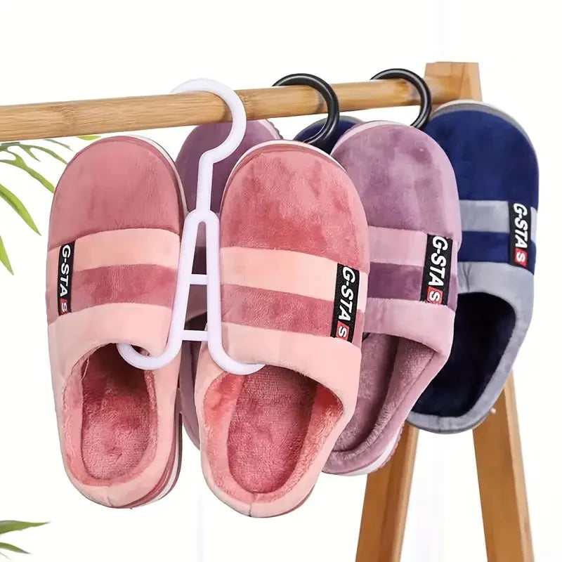 A set of portable plastic wig hangers in pink and purple colors hanging on a wooden rod.