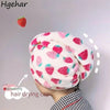A pink and white strawberry print quick-drying hair drying cap worn by a person.