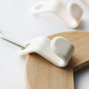 A white plastic clothes hanger hook is shown attached to a wooden hanger for wardrobe organization.