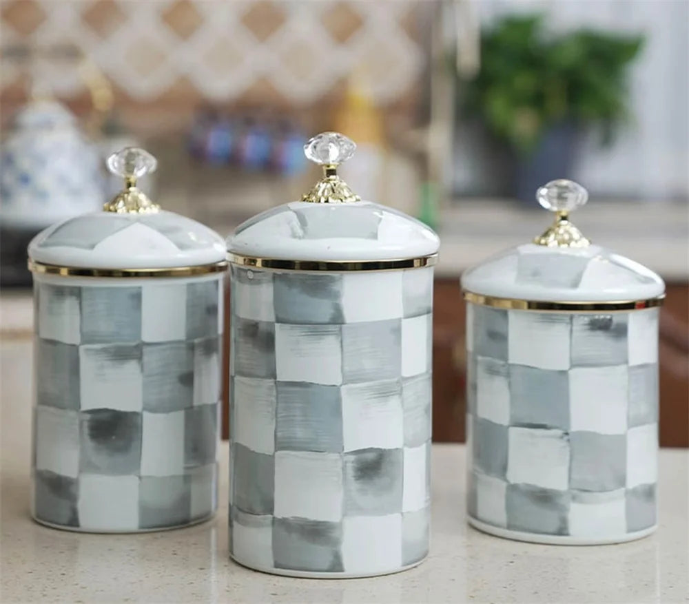 A set of three retro enamel storage jars with silver lids featuring a gray and white checkered pattern.