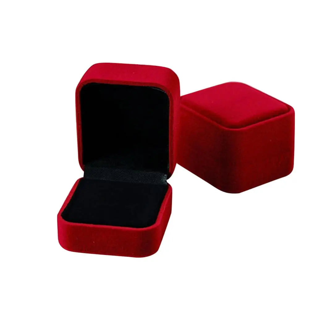 A square red velvet jewelry box with a hinged lid, shown from the side.