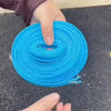 A hand is holding a spool of bright blue heavy-duty anti-slip windproof clothesline rope.