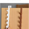 A hand is installing a white door hook rack onto a wooden closet door.