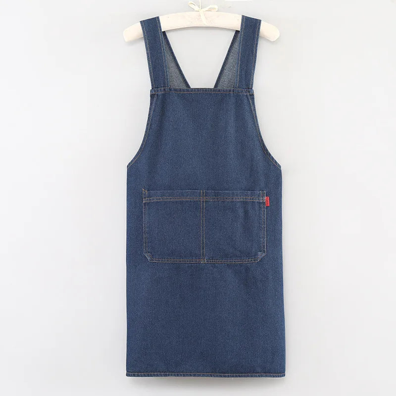 A dark blue denim apron with chest pockets hanging on a white hanger.