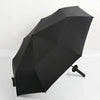 A black folding katana sword umbrella is shown angled on a white surface.