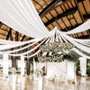 A wedding or event venue decorated with white sheer chiffon draping fabric suspended from the ceiling.
